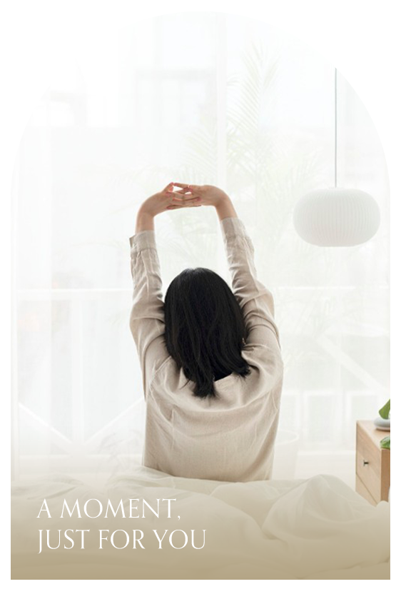 一位女性起床並在床邊悠閒的伸懶腰照片